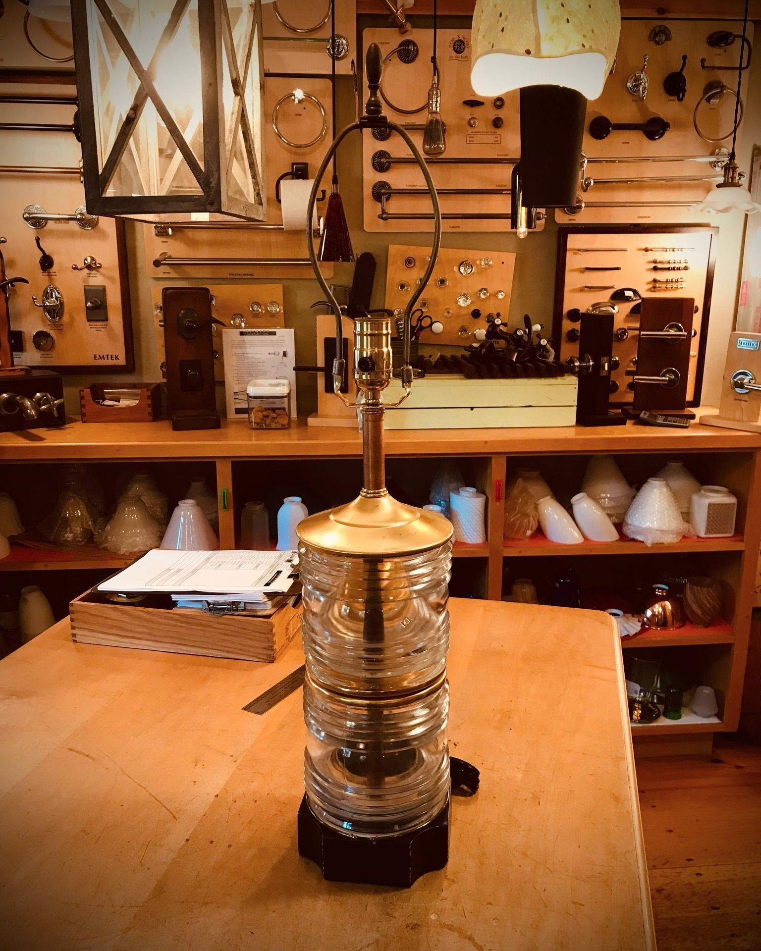 A decorative glass lamp on a wooden table in a workshop setting with lighting fixtures.