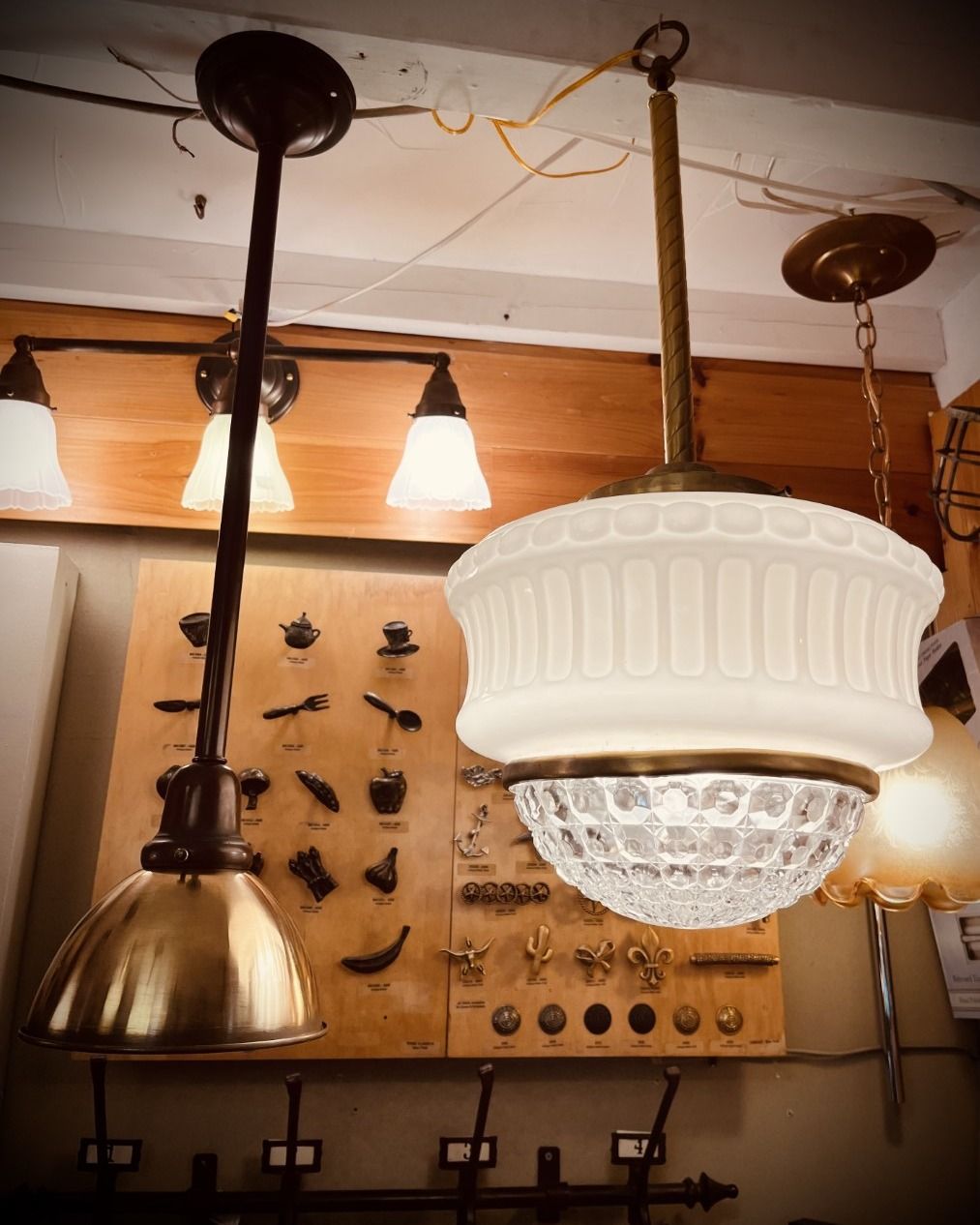 Two pendant lights with brass and glass shades in a shop setting.
