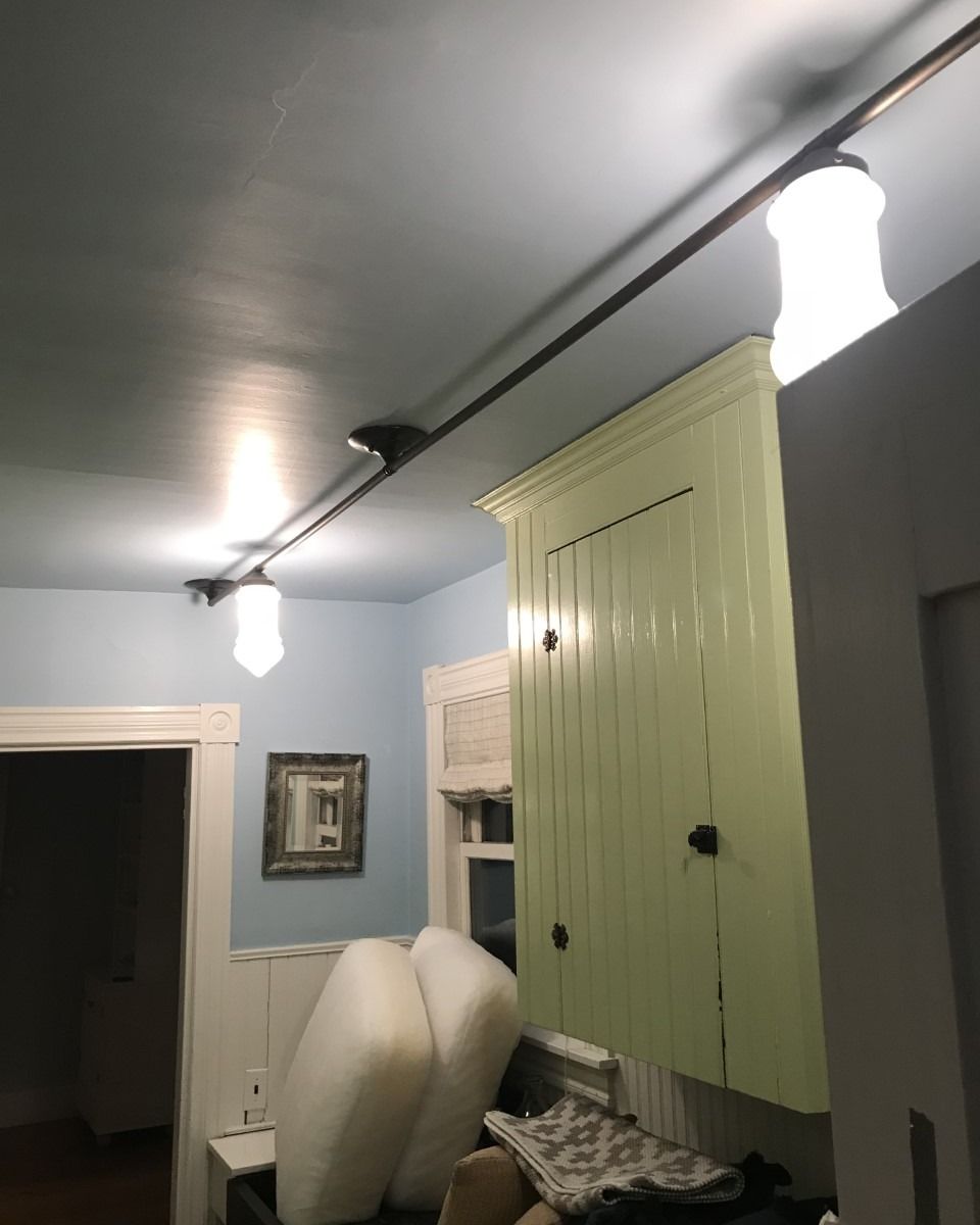 Ceiling with track lighting, above a pale green cabinet and blue walls.