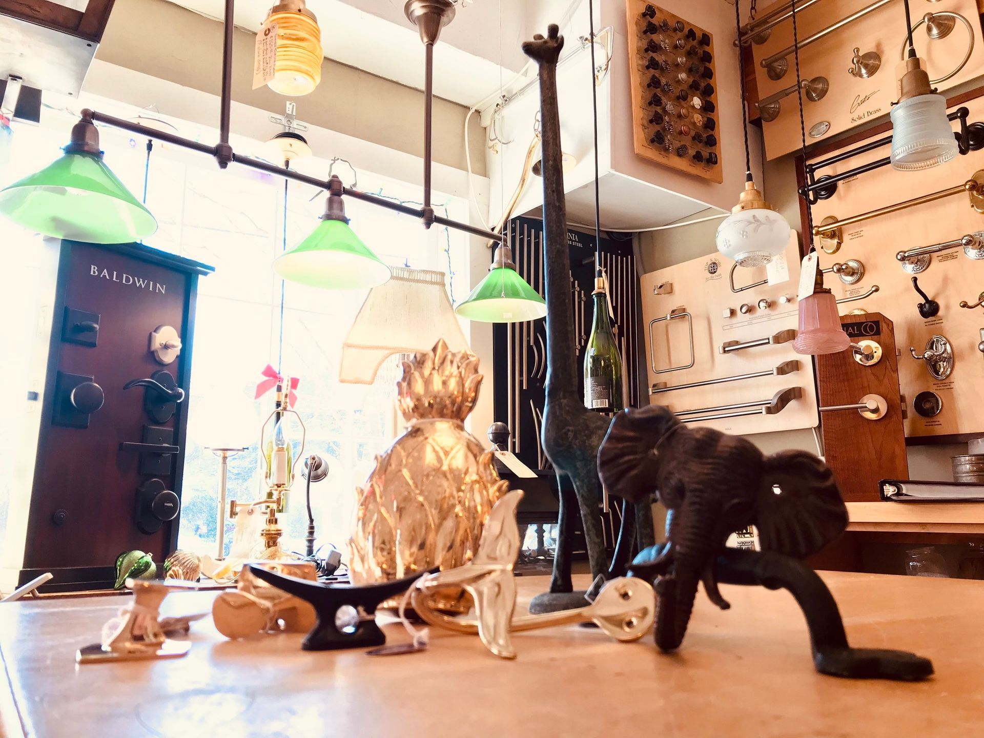 Display of decorative objects in a shop: lamps, giraffe and elephant statues. Green, white, and gold colors.