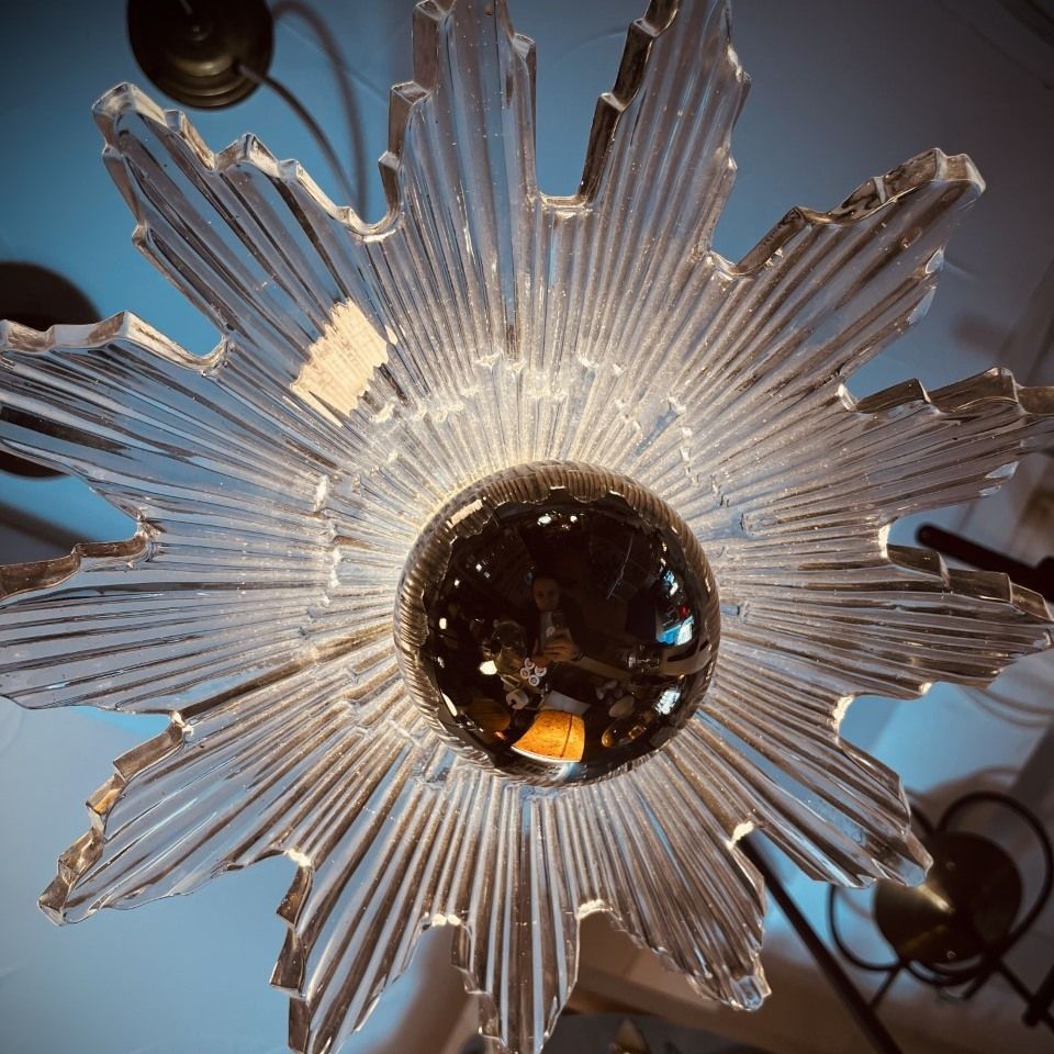 A starburst chandelier with a mirrored bulb center and radiating glass arms, viewed from below.