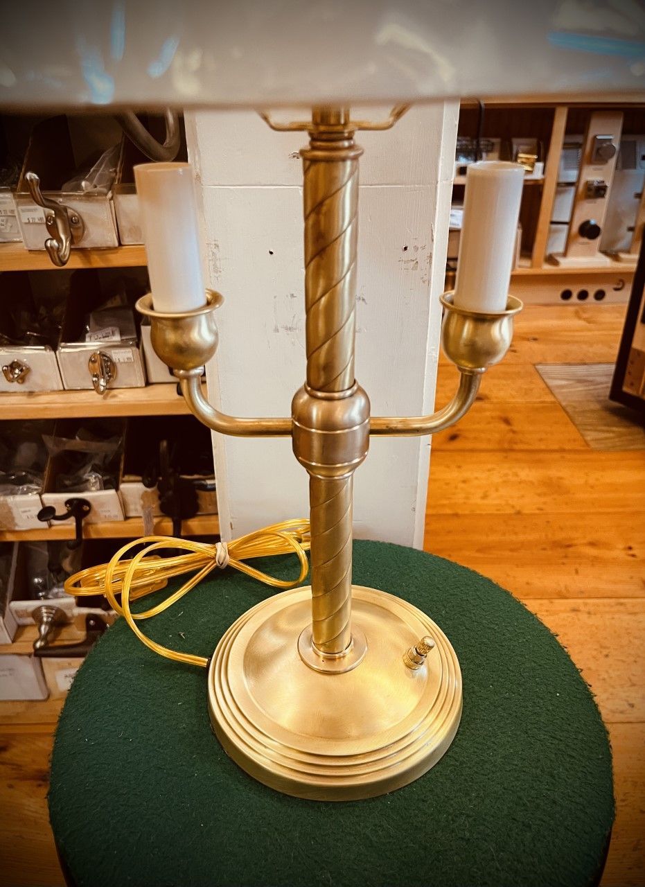 Brass desk lamp with twin bulb holders on a green surface.