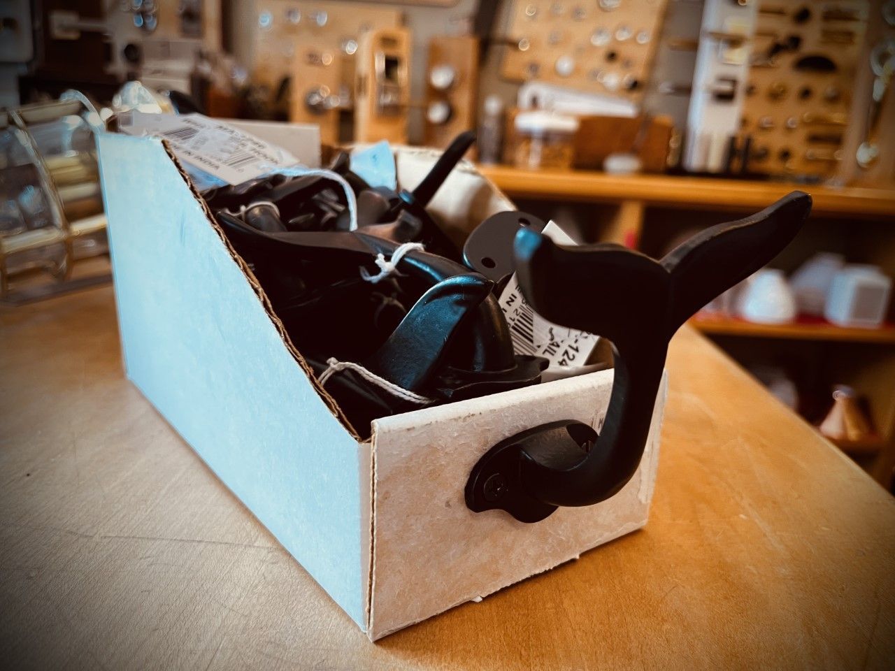 Cardboard box with a whale tail hook, full of black items, on a wooden surface.