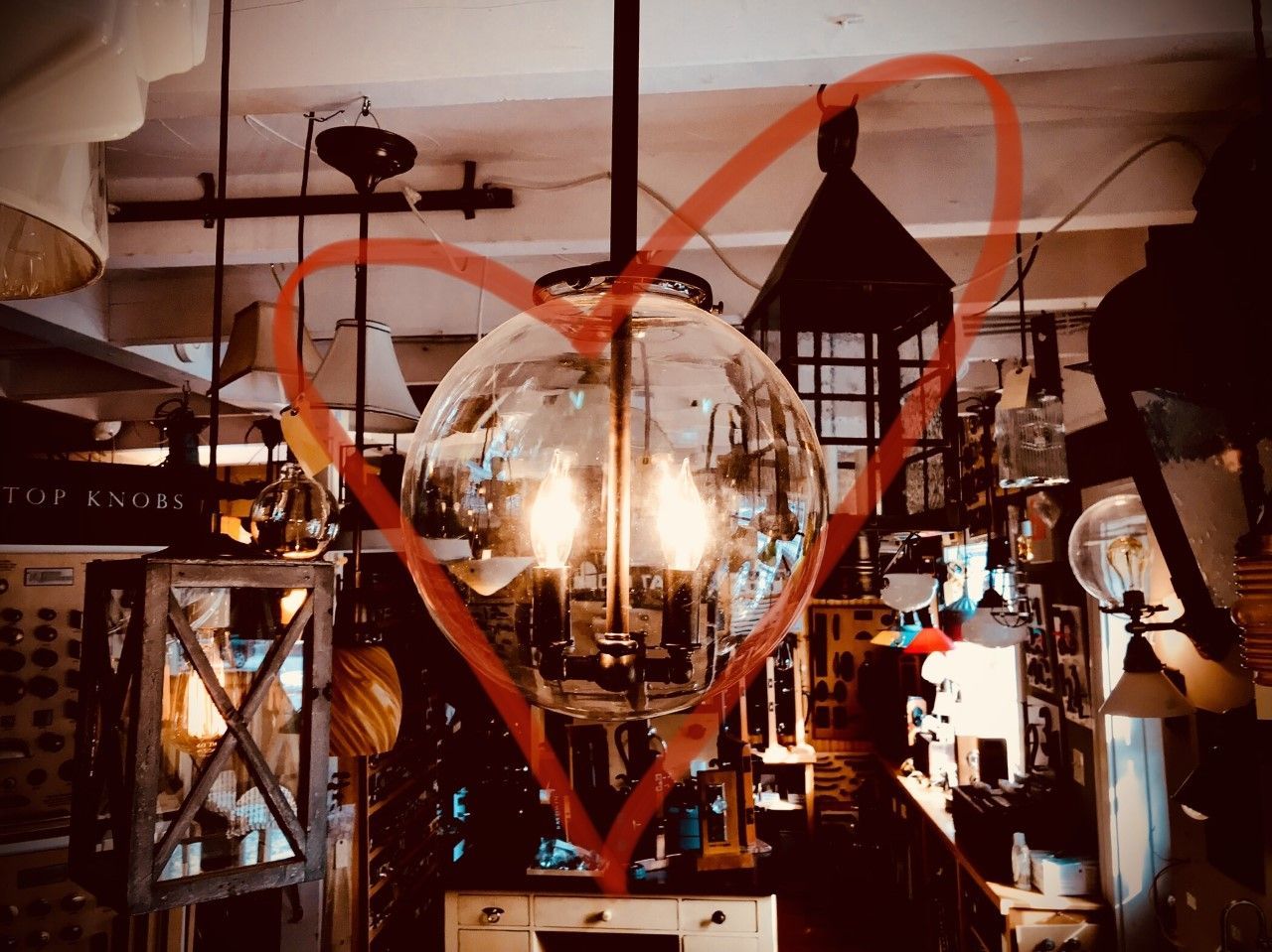 Large, round glass light fixture with visible bulbs, surrounded by other lamps in a store.