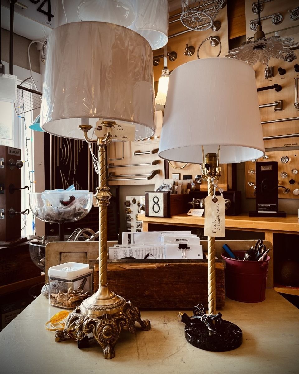 Two decorative lamps with lampshades on a table in a shop setting.