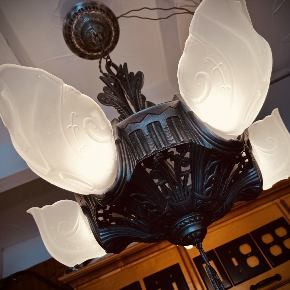 Antique bronze chandelier with frosted glass shades, hanging indoors.