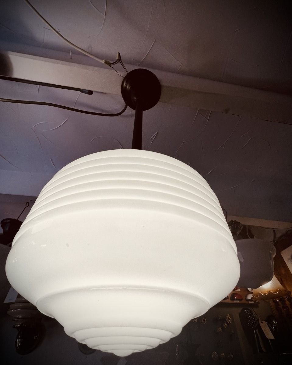 White, tiered glass pendant light hanging from a dark, circular ceiling mount.