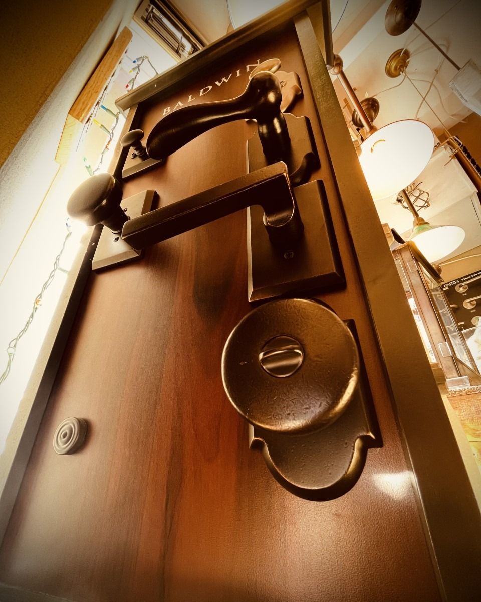 Close-up view of a dark wooden door with ornate hardware, including a handle, lock, and knocker.