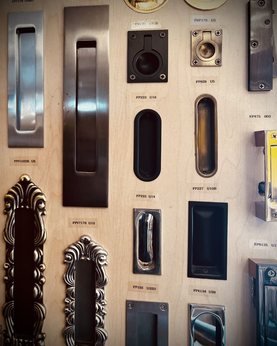 Display of various metal door handles mounted on a light wooden surface.
