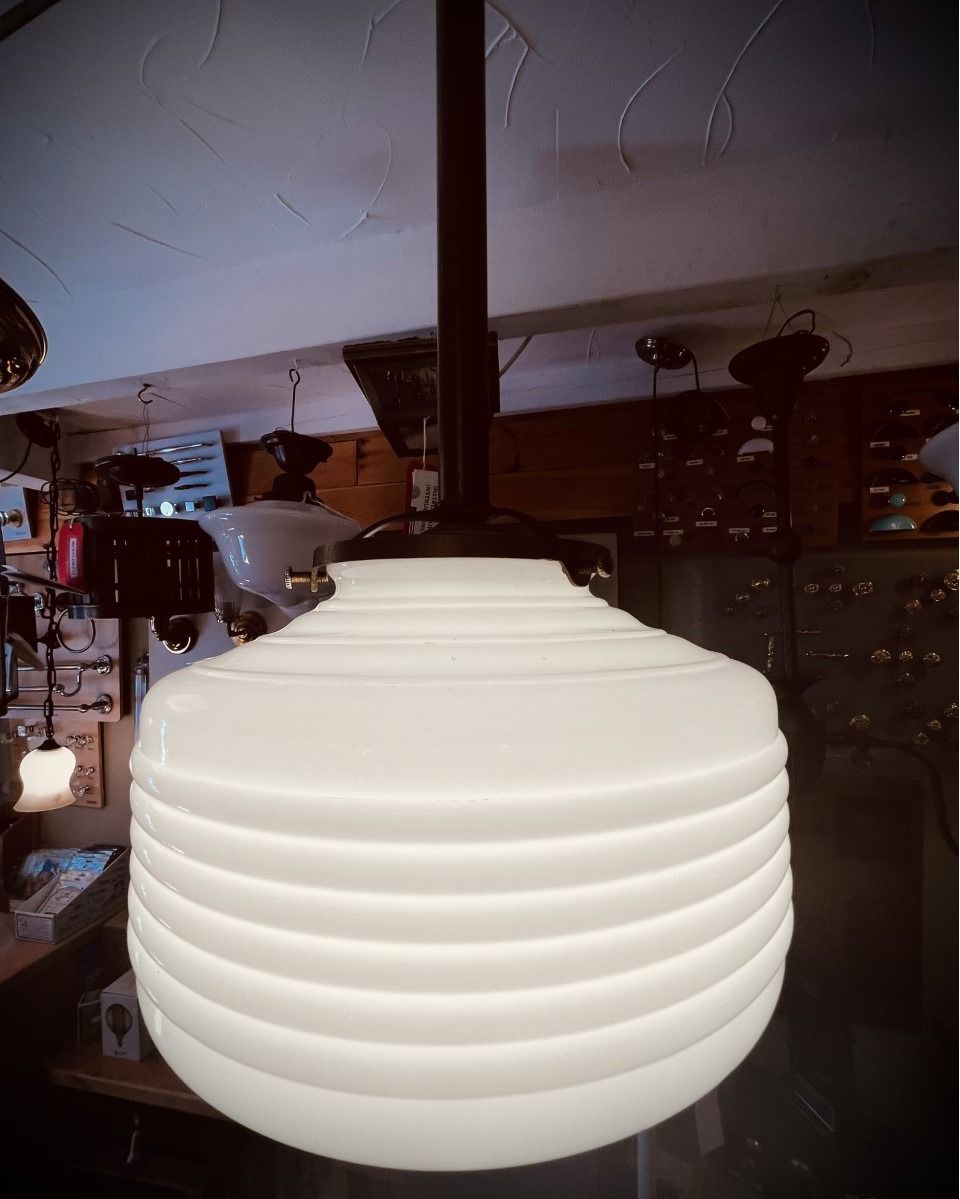 White, ribbed glass pendant light fixture with dark metal stem, hanging in a room.