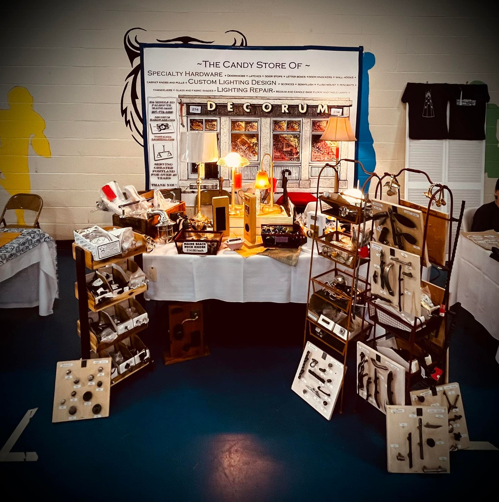 A vendor's booth with various vintage items for sale at a market, including art, lamps, and tools.