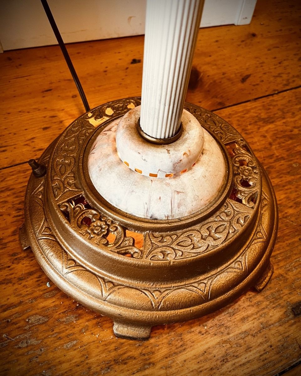 Close-up of a vintage floor lamp base with ornate floral and scrollwork designs.
