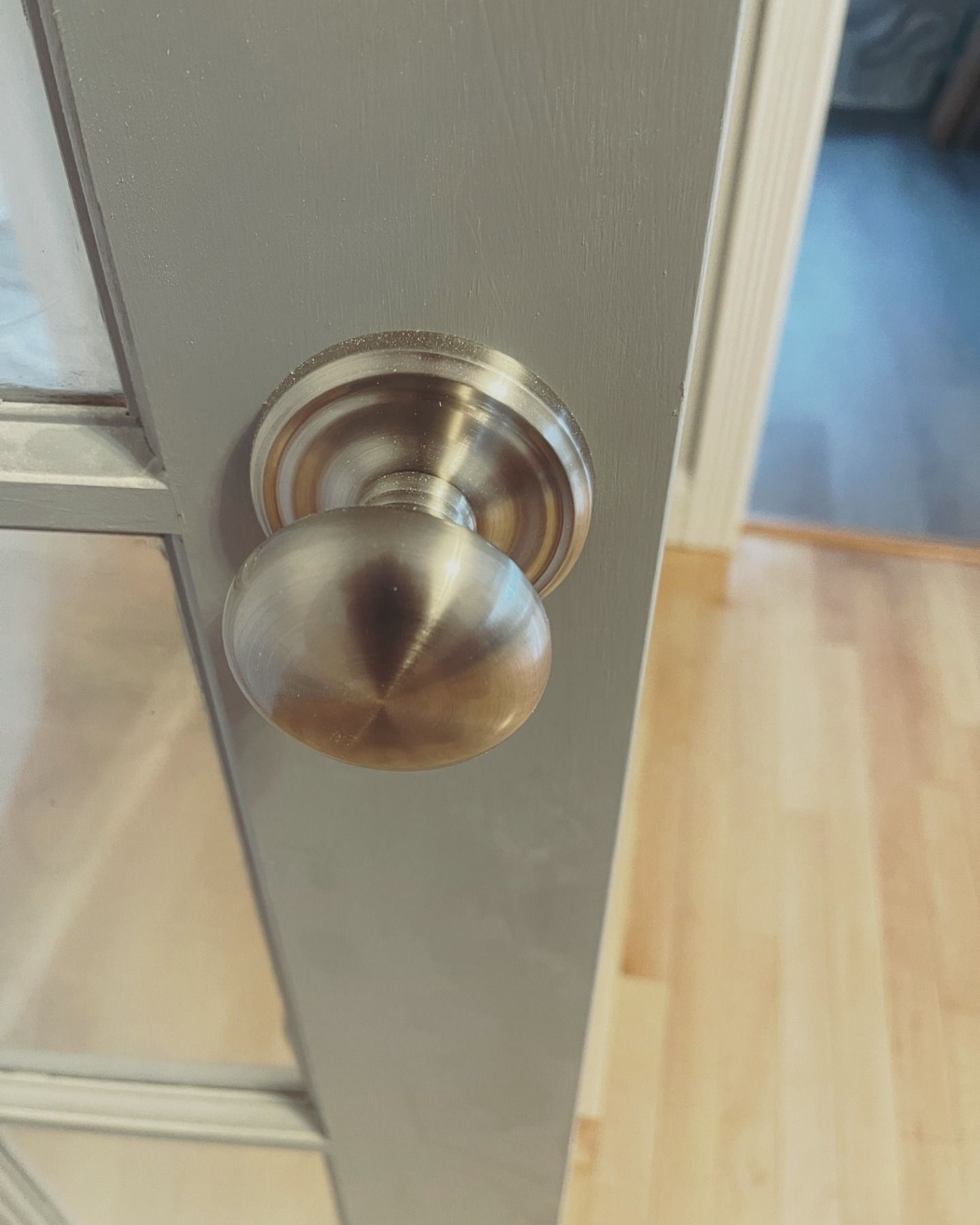 Silver door knob on a gray door; wood floor visible in the background.