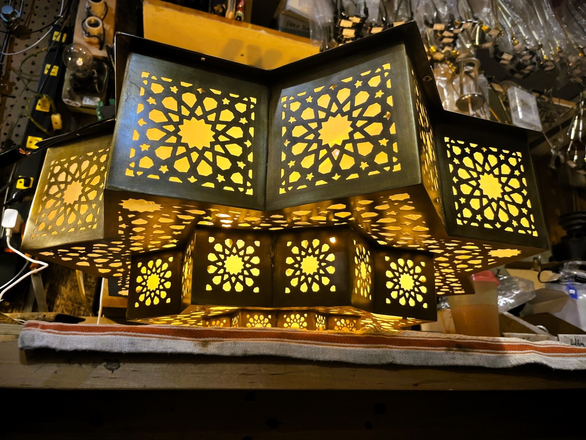 Geometric, star-patterned metal lamp with warm yellow light glowing through cutouts.