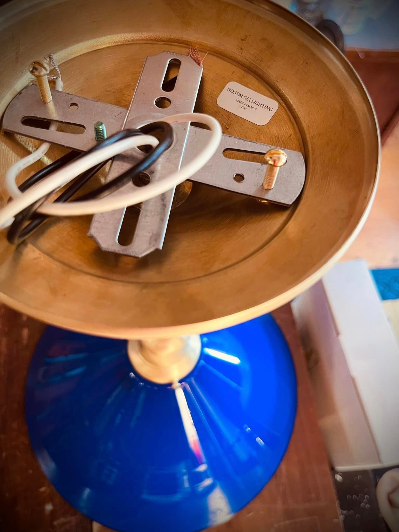 Blue glass pendant light with brass-colored top, showing wiring and mounting bracket.