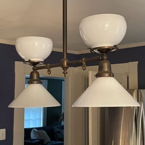 Two-light pendant lamp with white glass shades and bronze finish, hanging in a kitchen.