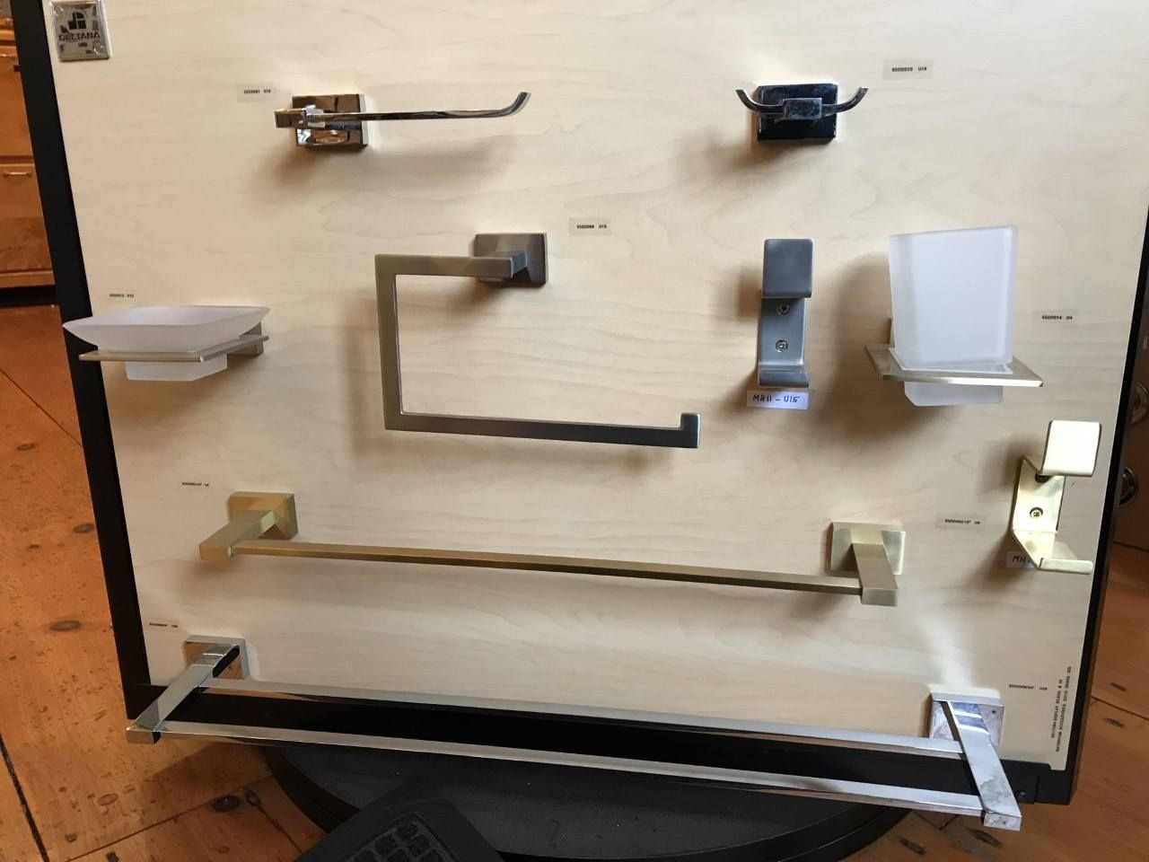 Bathroom hardware display: various towel racks, soap dishes, and other fixtures mounted on a wooden board.