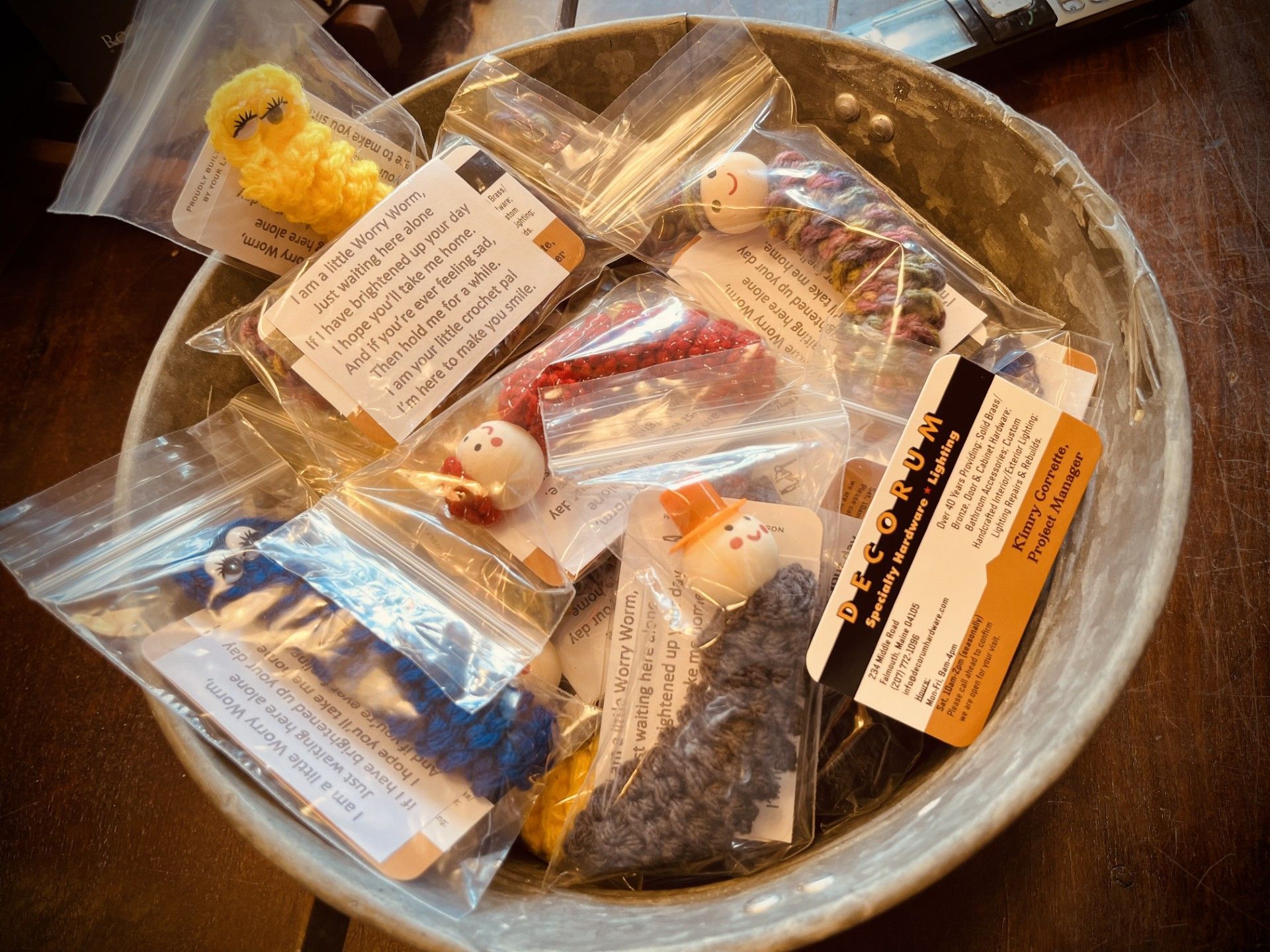 Bowl filled with small, bagged yarn creatures with attached tags.