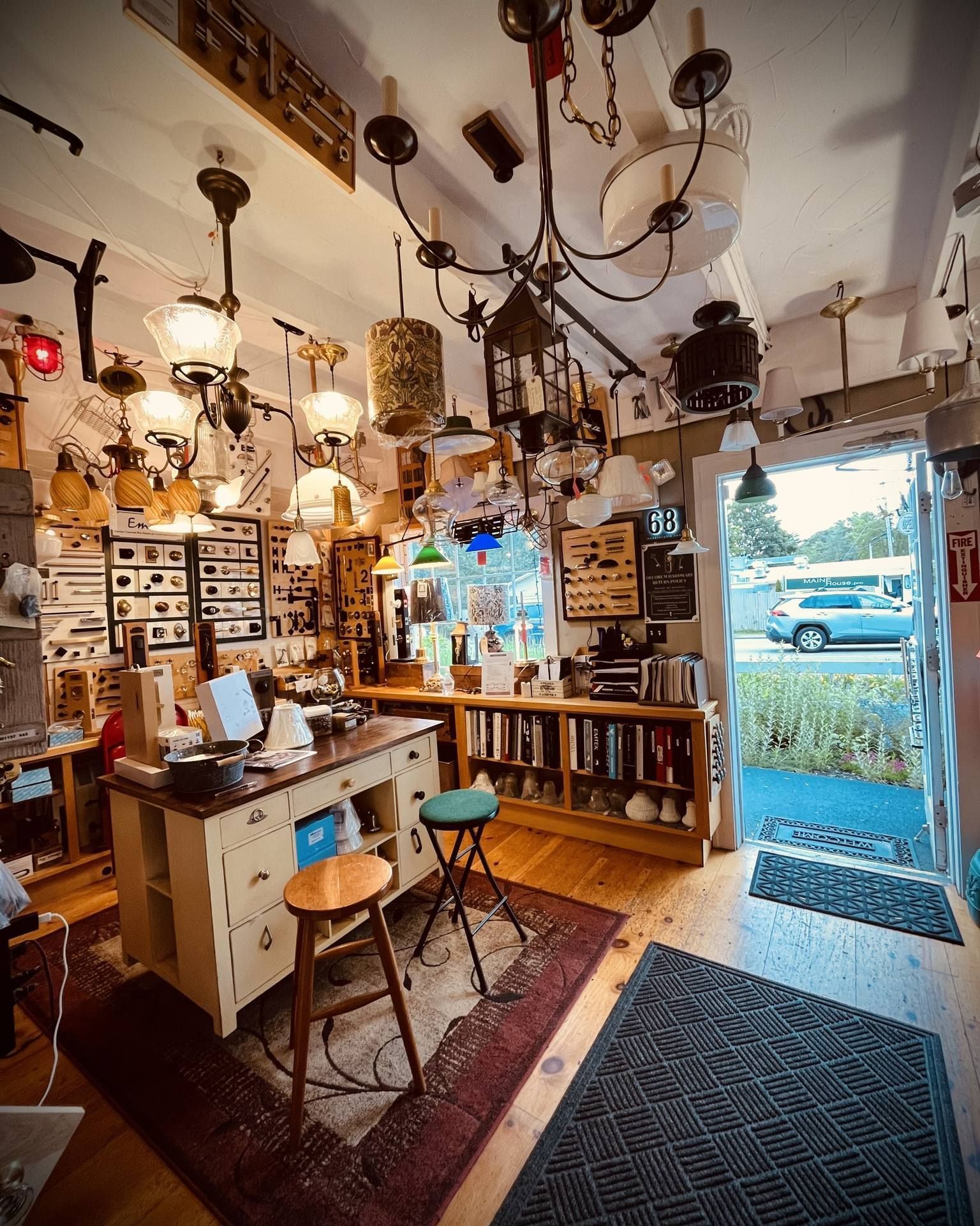 A well-lit antique lamp shop interior with many hanging light fixtures. A doorway is visible to the right.