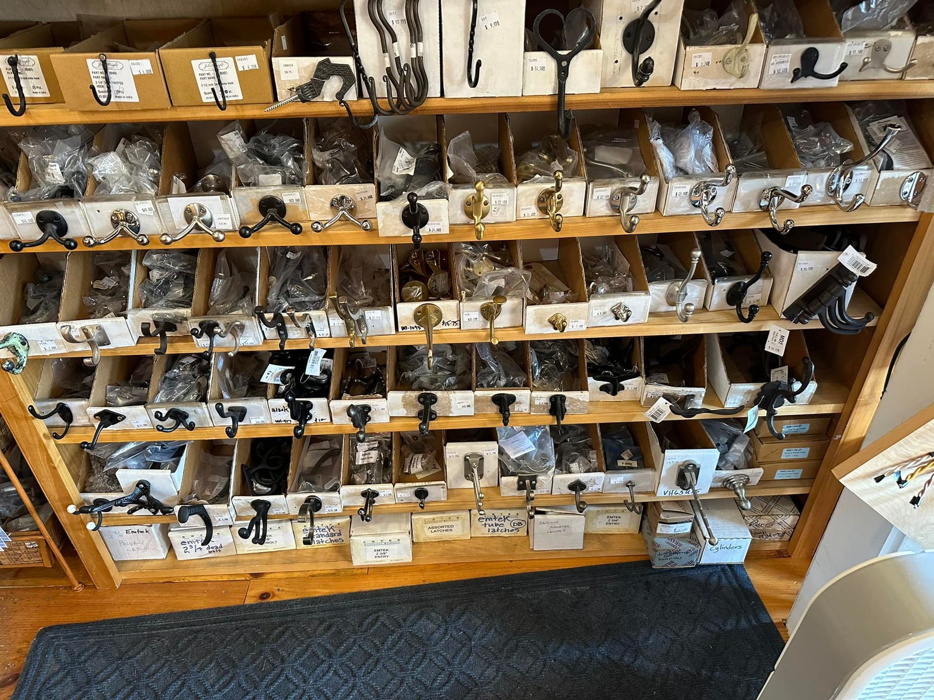 Wooden shelves filled with hardware items in organized bins. Many hooks and knobs are visible.