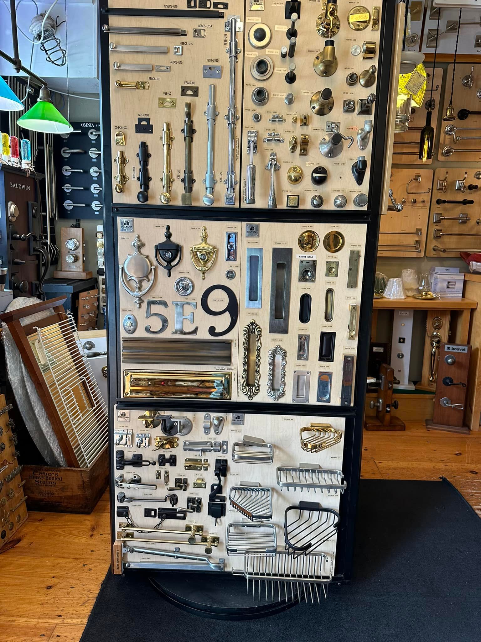 Display of door hardware, including knobs, handles, and knockers, arranged on a black framed board inside a hardware store.