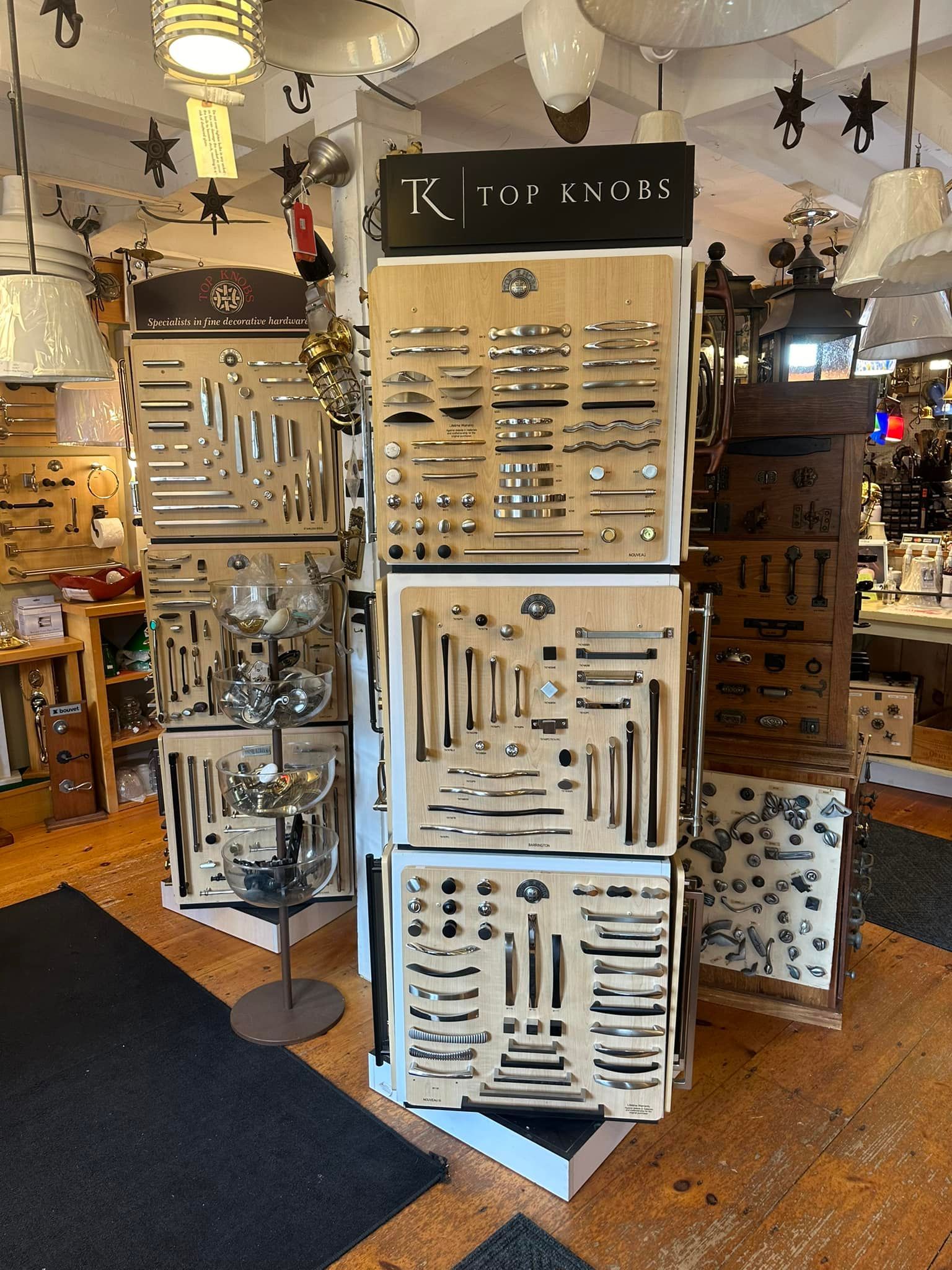 Display of cabinet hardware in a store. Wooden displays show various knobs and pulls in silver and black.