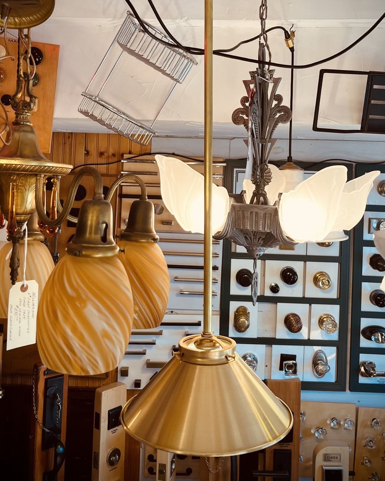 Antique lighting fixtures displayed in a shop, including a gold cone-shaped pendant lamp and other ornate fixtures.
