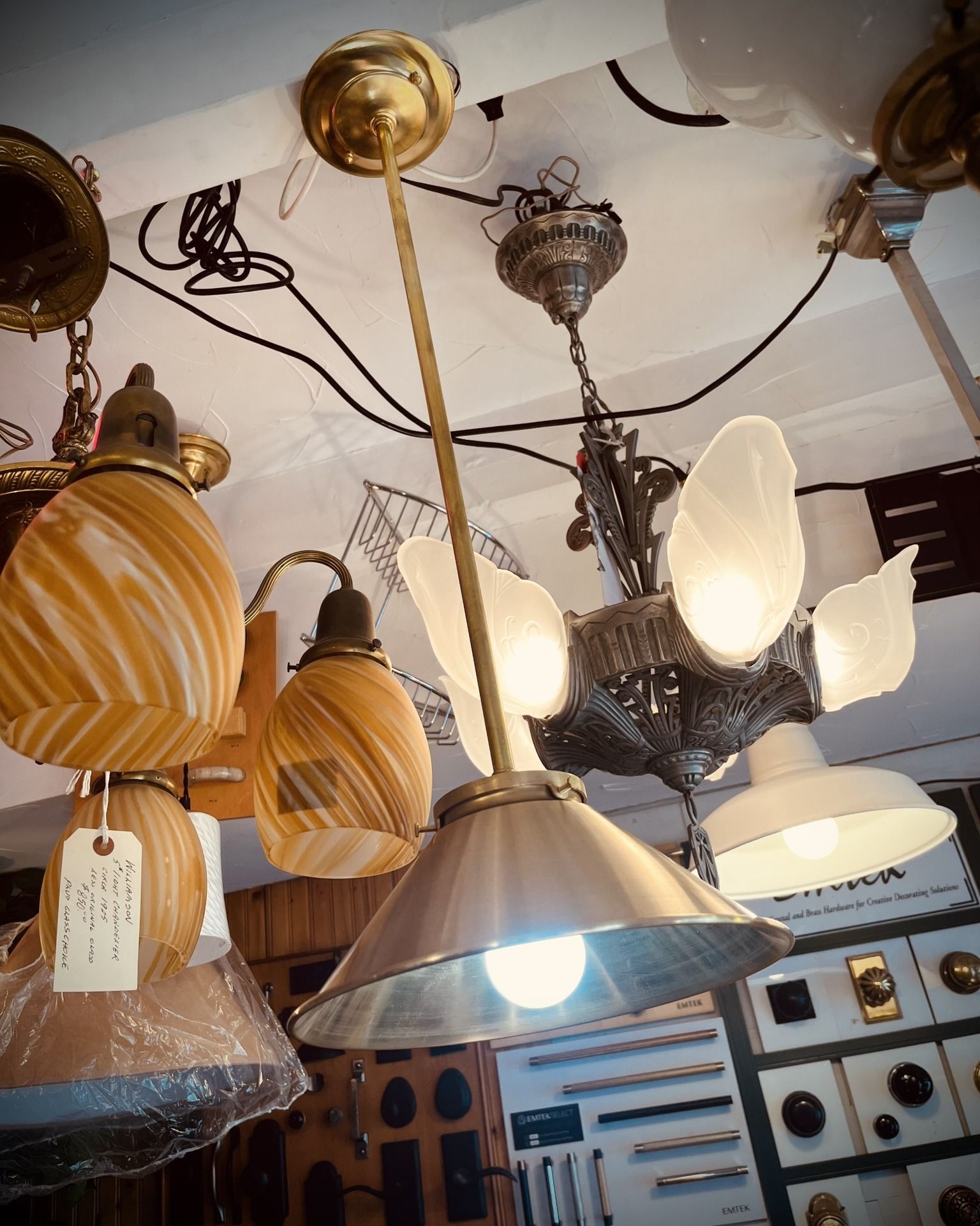 Ceiling lights display in an antique store. Various vintage fixtures in gold, silver, and glass.