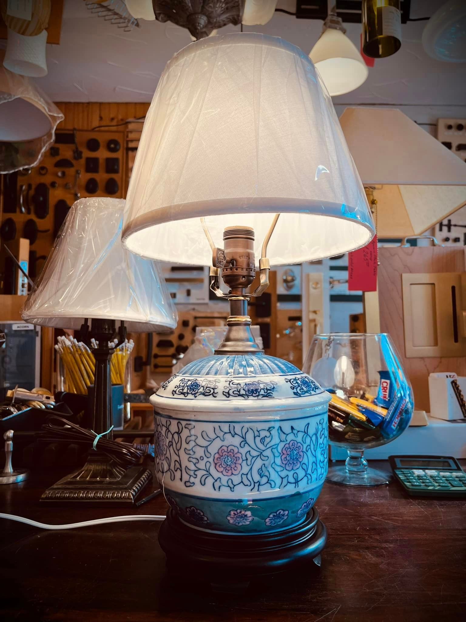 Blue and white porcelain lamp with lampshade on a table, other lamps in background.