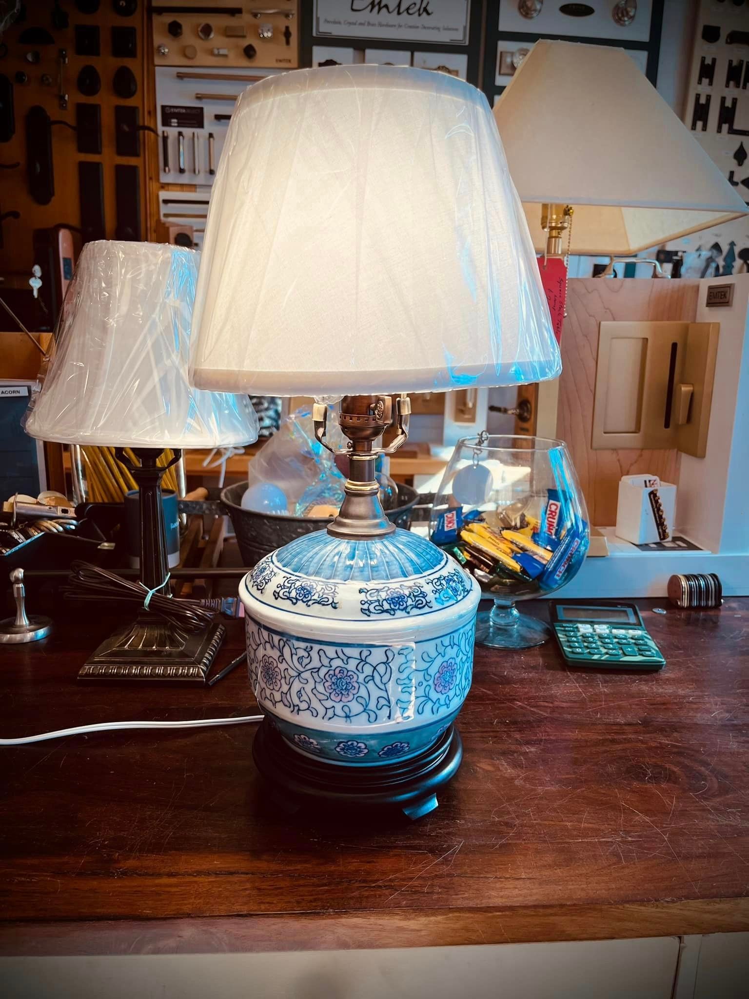 Blue and white patterned lamp with a lampshade on a wooden surface with other lamps.