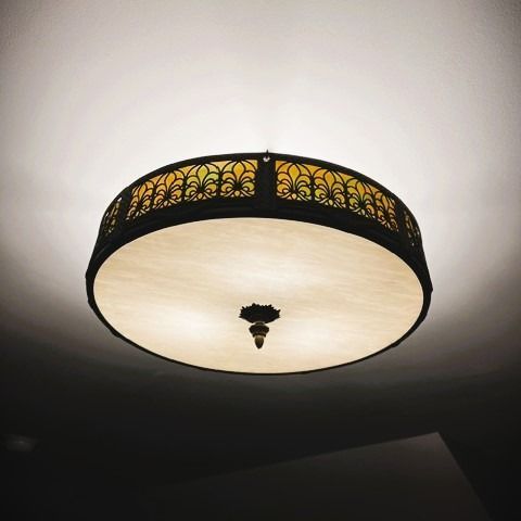 Ornate, round ceiling light fixture with a decorative metal filigree rim and a pale, translucent shade.