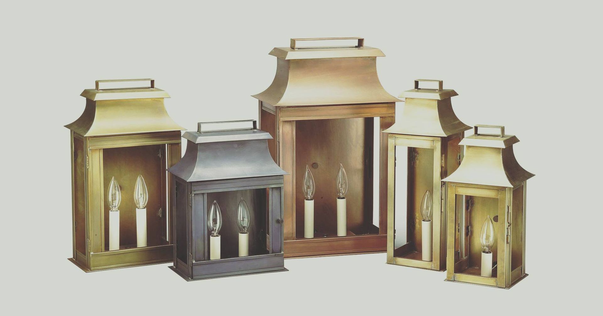 Five brass and copper outdoor wall-mounted lanterns, various sizes, each with two candle-shaped lights.