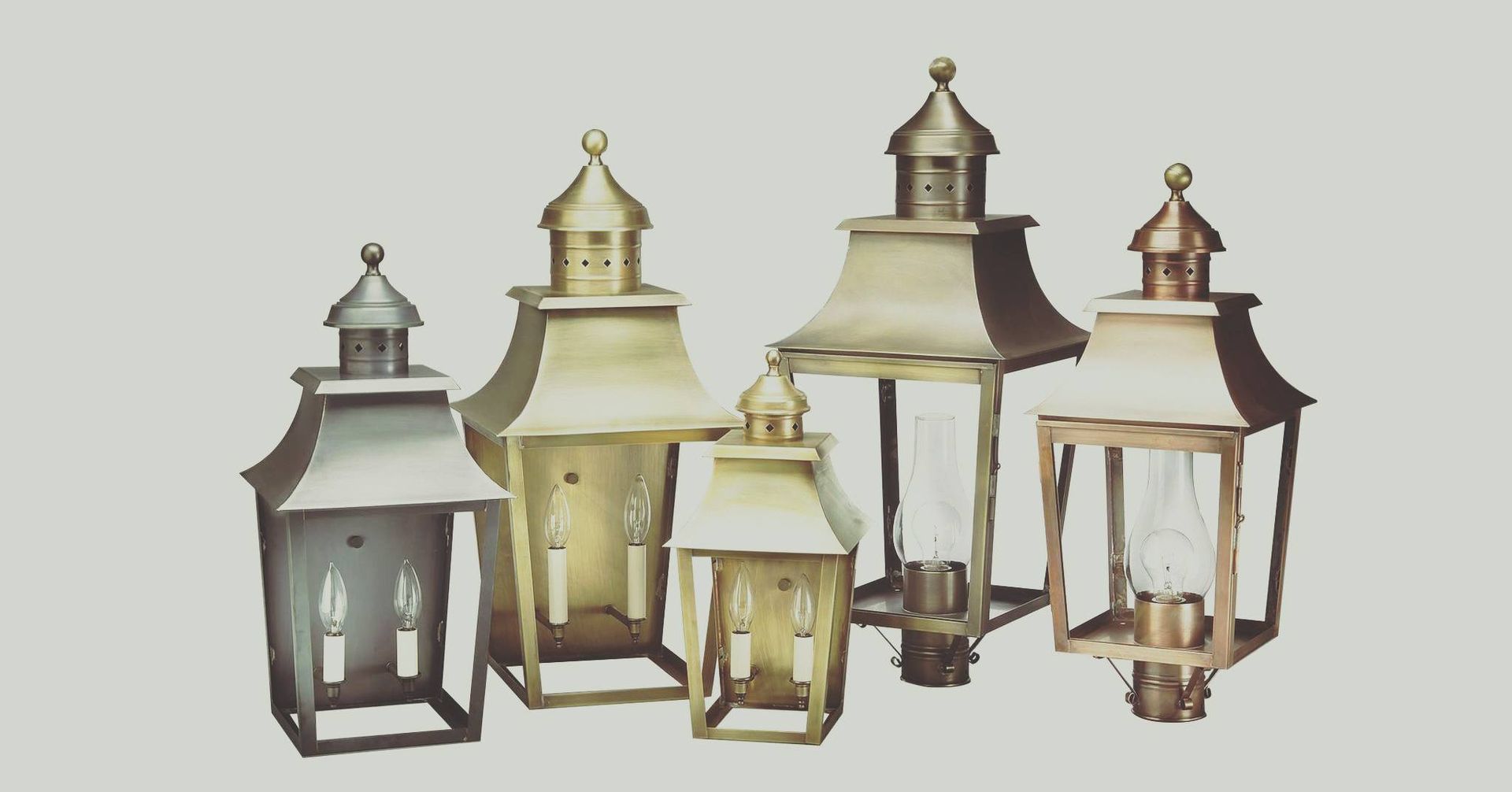 Five brass outdoor lanterns of varying sizes against a light background.