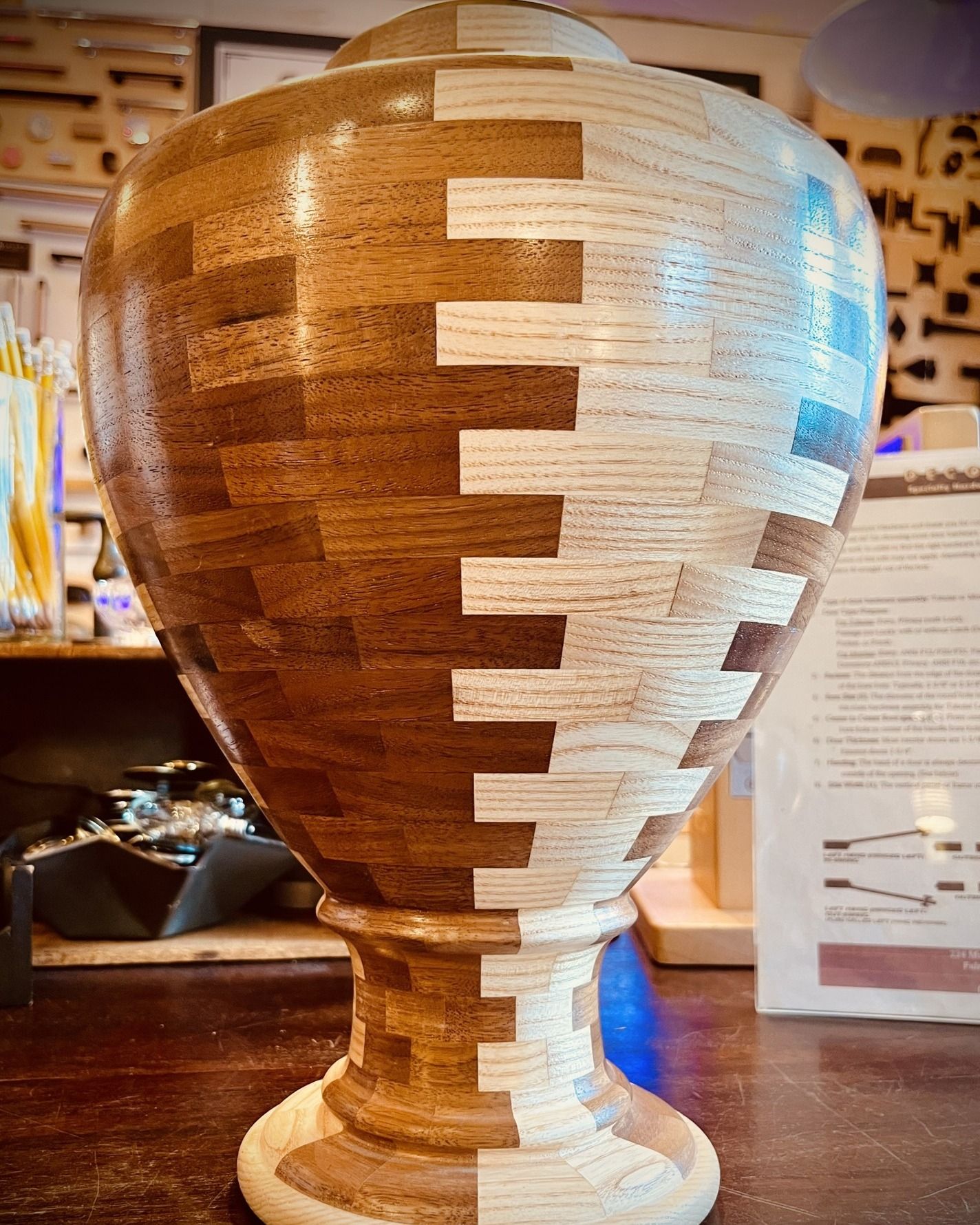 Wooden urn split vertically into two colors with interlocking pattern.