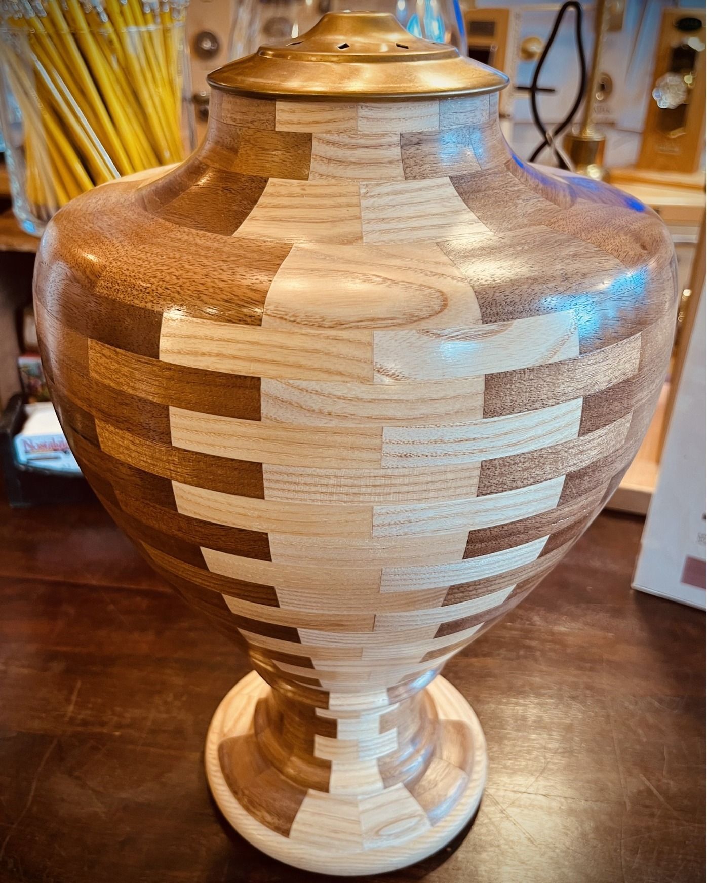Wooden urn with a geometric design in light and dark wood tones.