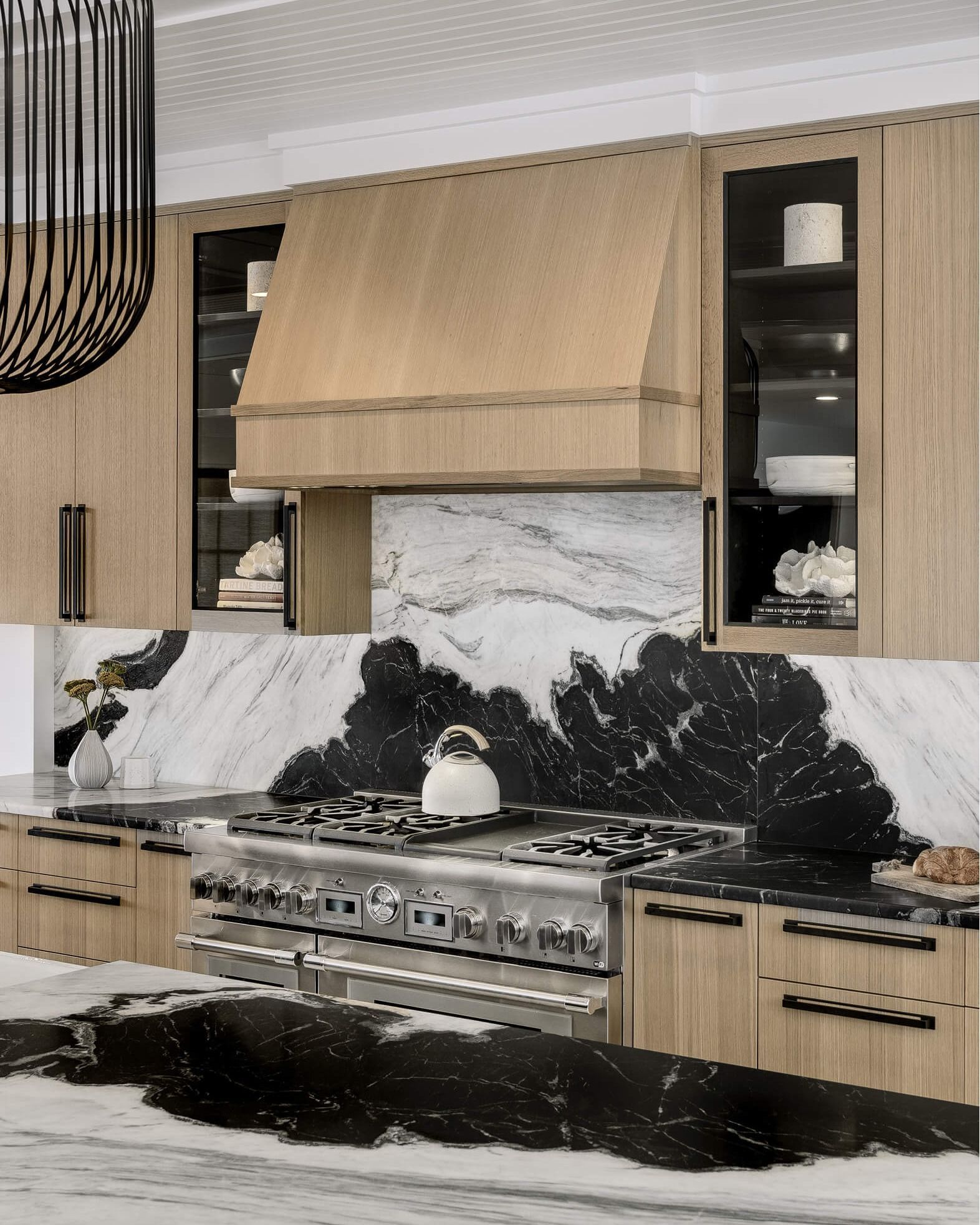 Modern kitchen with wood cabinets, marble backsplash and countertops, and stainless steel appliances.