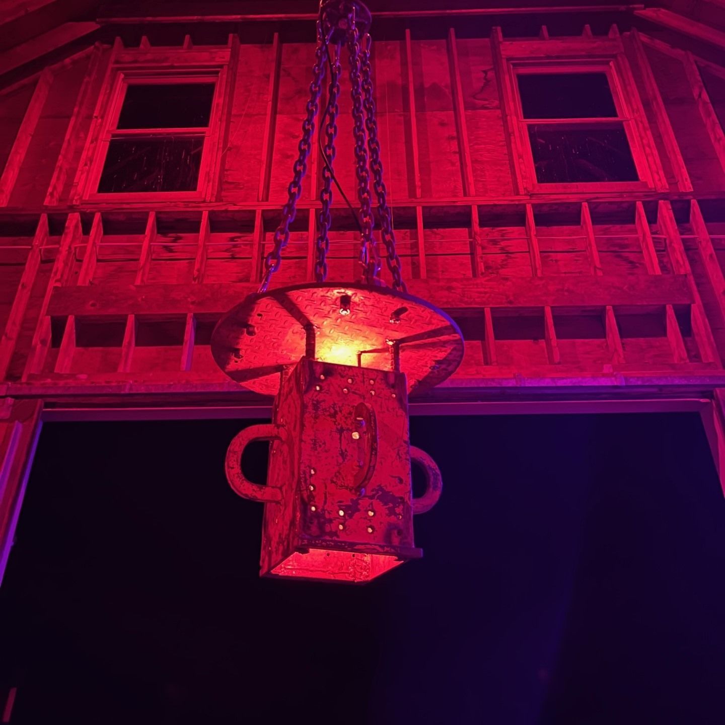 Red-lit barn interior with a hanging, rusty metal lantern. Two small windows above the entrance.