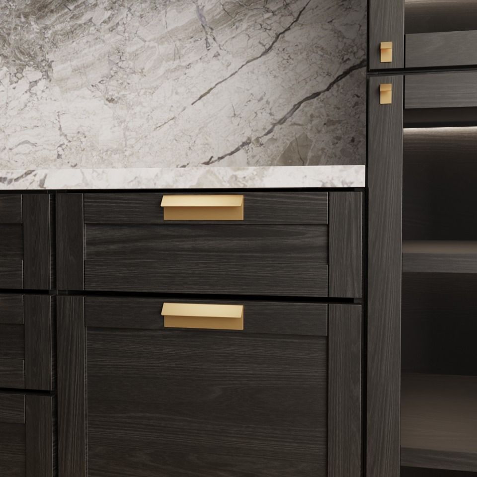 Dark wood kitchen cabinets with gold handles against marble backsplash.