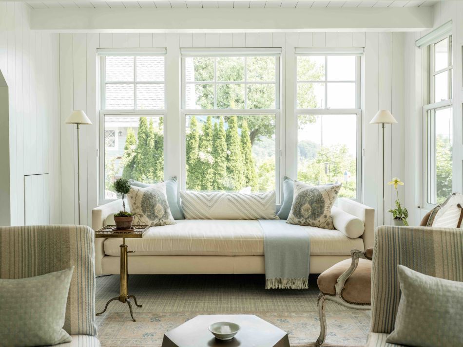 Bright living room with large windows, cream sofa, and light blue accents.