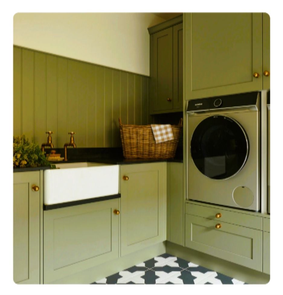 Green laundry room with cabinetry, farmhouse sink, washer, and patterned floor.