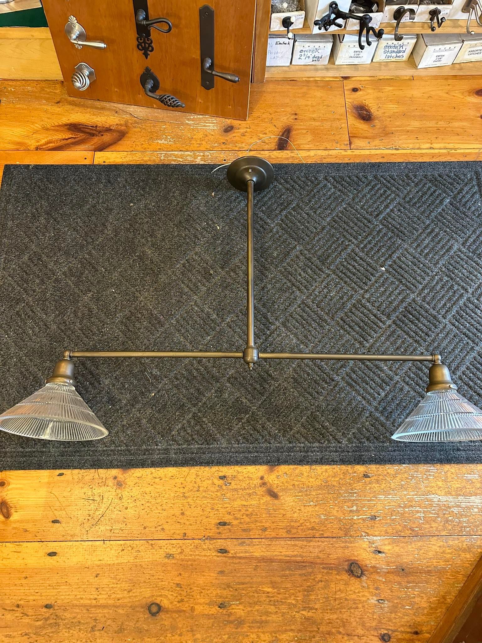 Brass two-bulb light fixture with textured glass shades on gray rug over wood.