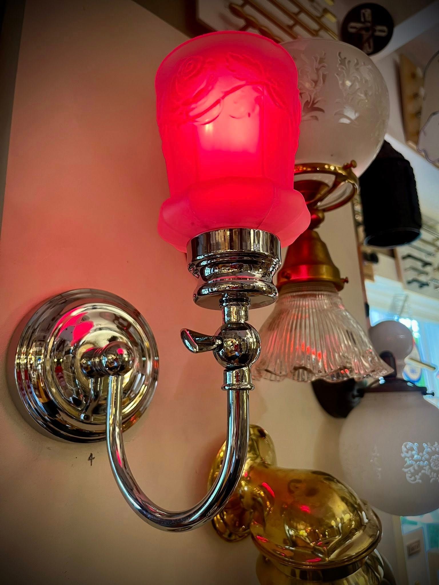 Silver sconce with pink frosted glass shade.