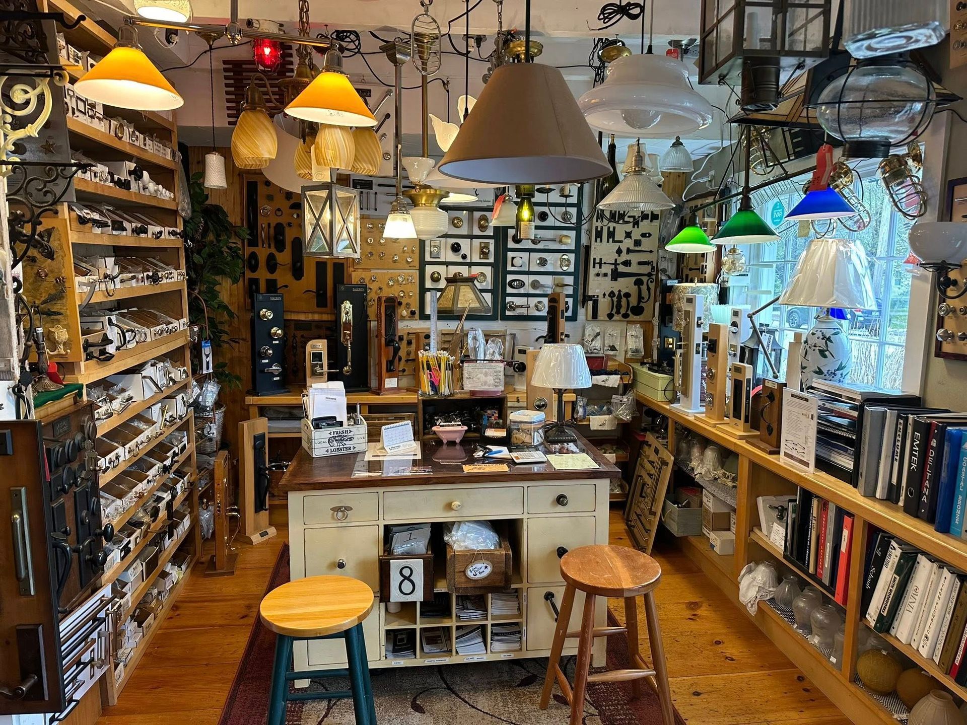 Interior shot of a shop filled with various lamps and light fixtures, with shelves and a central counter.