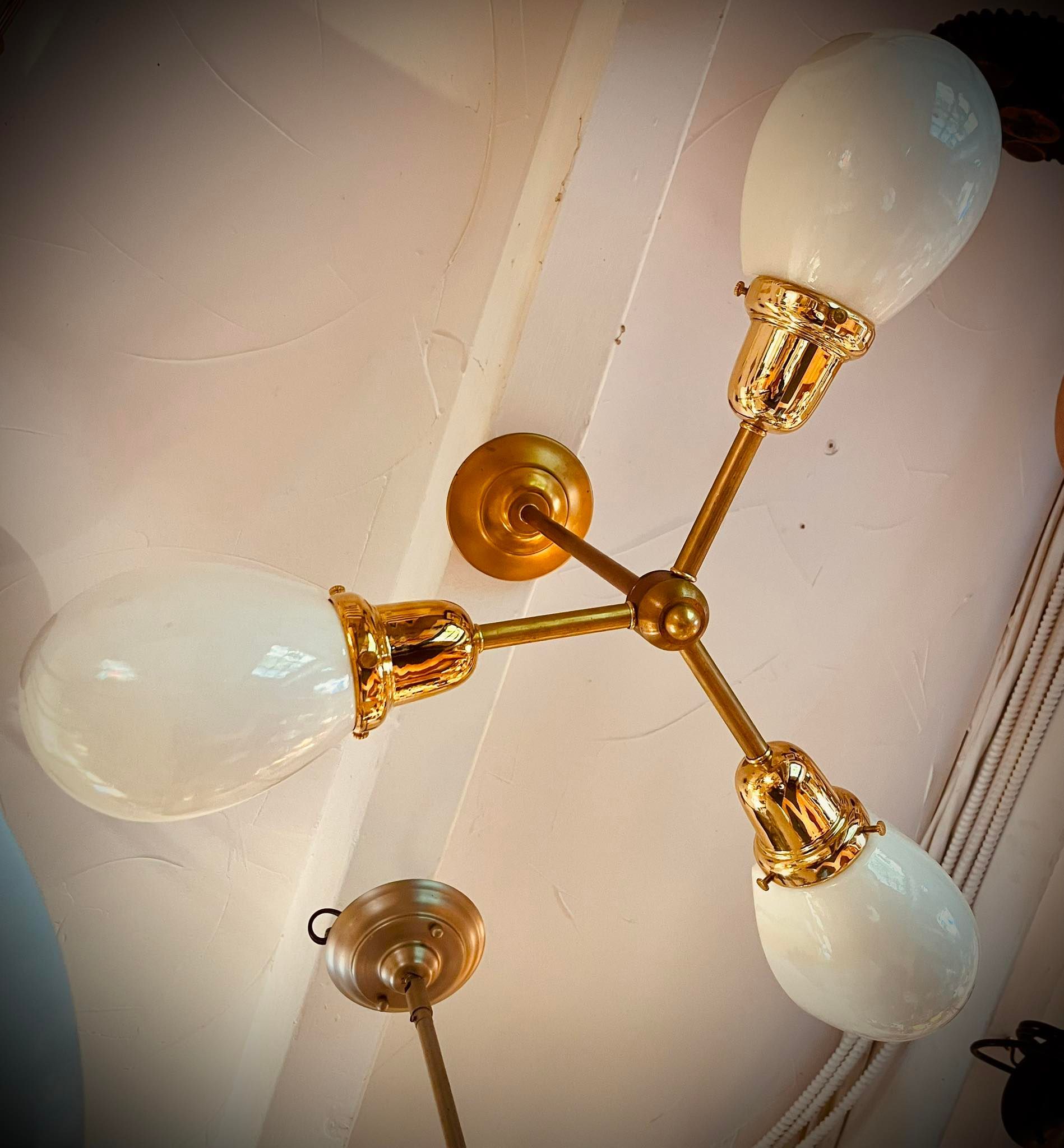 Three-light ceiling fixture with white teardrop-shaped glass shades and gold accents.