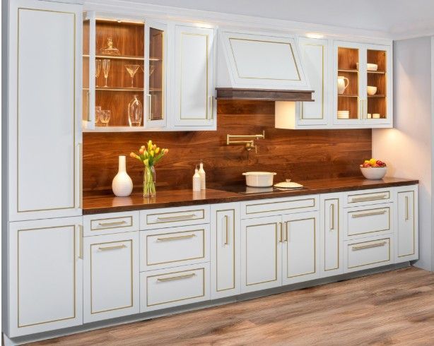 White kitchen cabinets with gold trim and wood backsplash.