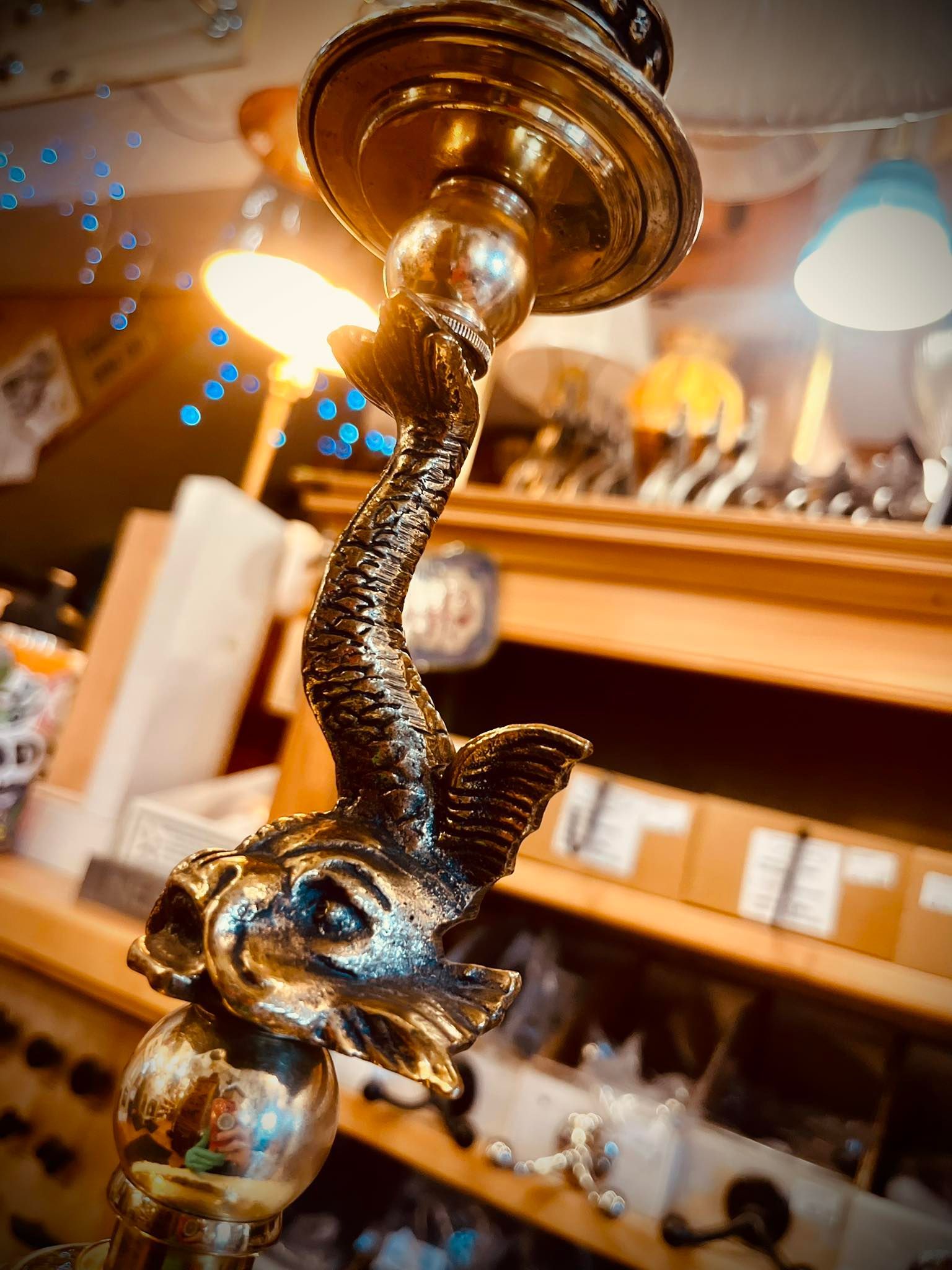 Brass elephant-shaped candlestick with curved trunk, holding a light socket, in a shop setting.
