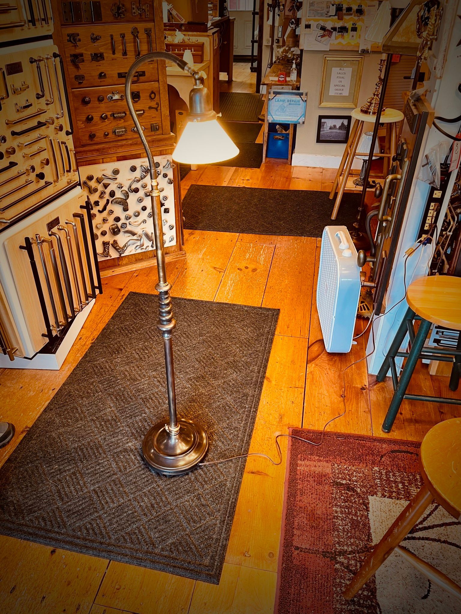 Floor lamp in room with wooden floors, rugs, and various items.