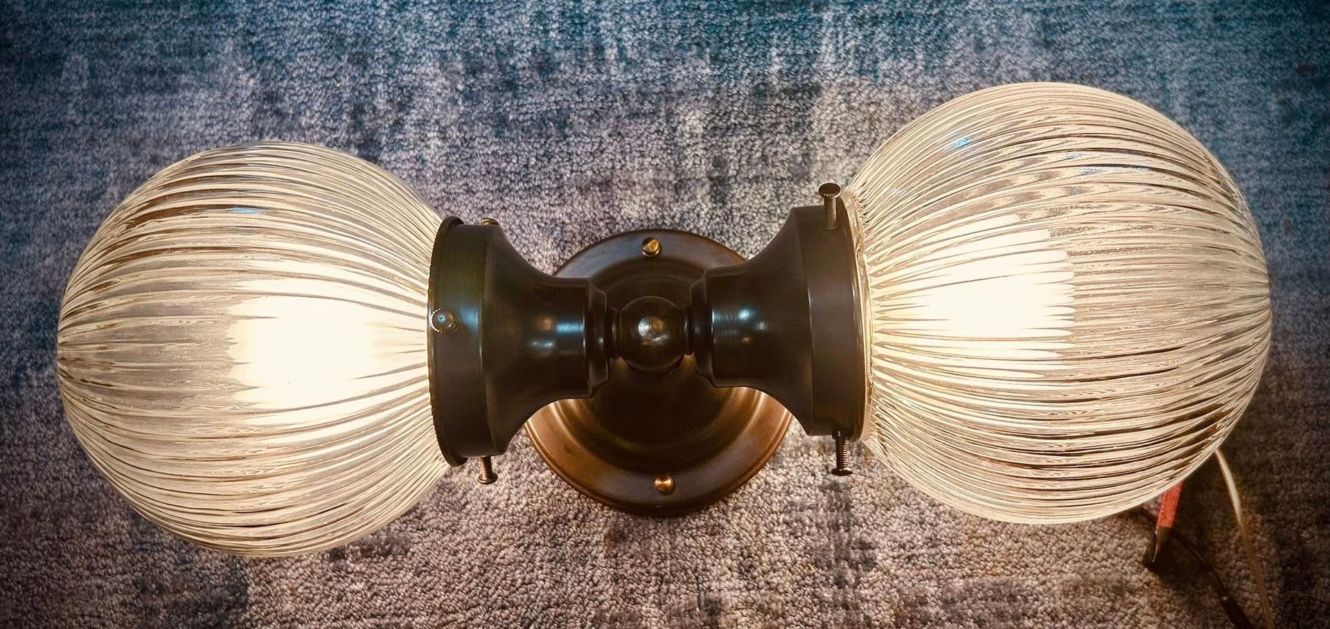 Double globe wall light fixture on a textured wall.