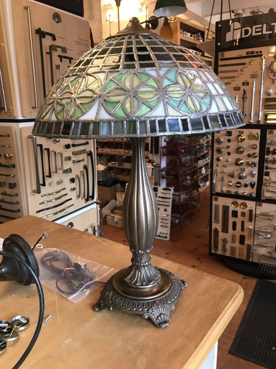 Tiffany-style table lamp with stained glass shade, on a wooden surface in a store.