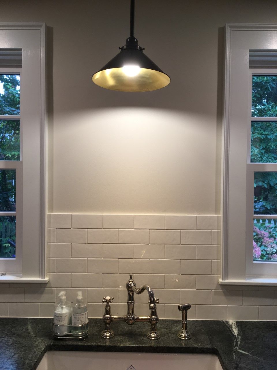Kitchen sink with pendant light above, windows on either side.